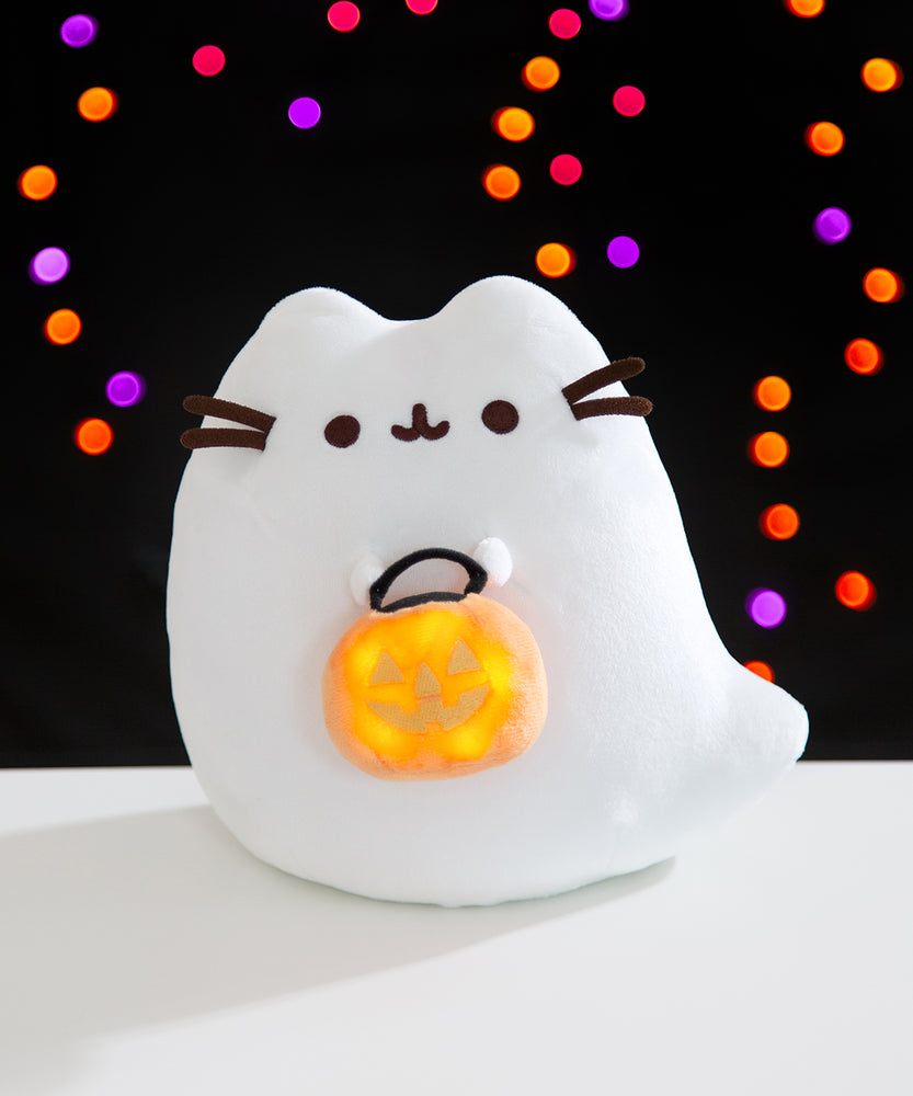 Front view of the Boosheen Plush with the pumpkin candy pail light-up feature turned on. The plush has a button to turn the lights in the candy pail on and off.