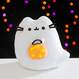 Front view of the Boosheen Plush with the pumpkin candy pail light-up feature turned on. The plush has a button to turn the lights in the candy pail on and off.