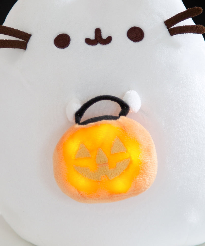 Close-up view of the light-up feature on the Halloween Cat plush. The round orange candy pail has five lights to illuminate the jack-o'-lantern trick-or-treat pail.