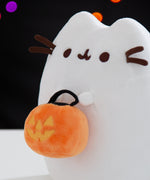 Close-up view of the side of the Boosheen plush. The white ghost plush has 3D brown whiskers that extend off the plush toy. Pusheen's two front paws extend off the front of the plush and hold the trick-or-treat candy pail.