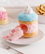 Side view of the Sprinkle Cake Plush. The removable interior plush rests in front of the cake environment. The little pink plush has multi-colored sprinkles embroidered on the booty area of the cat.  