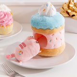 Side view of the Sprinkle Cake Plush. The removable interior plush rests in front of the cake environment. The little pink plush has multi-colored sprinkles embroidered on the booty area of the cat.  