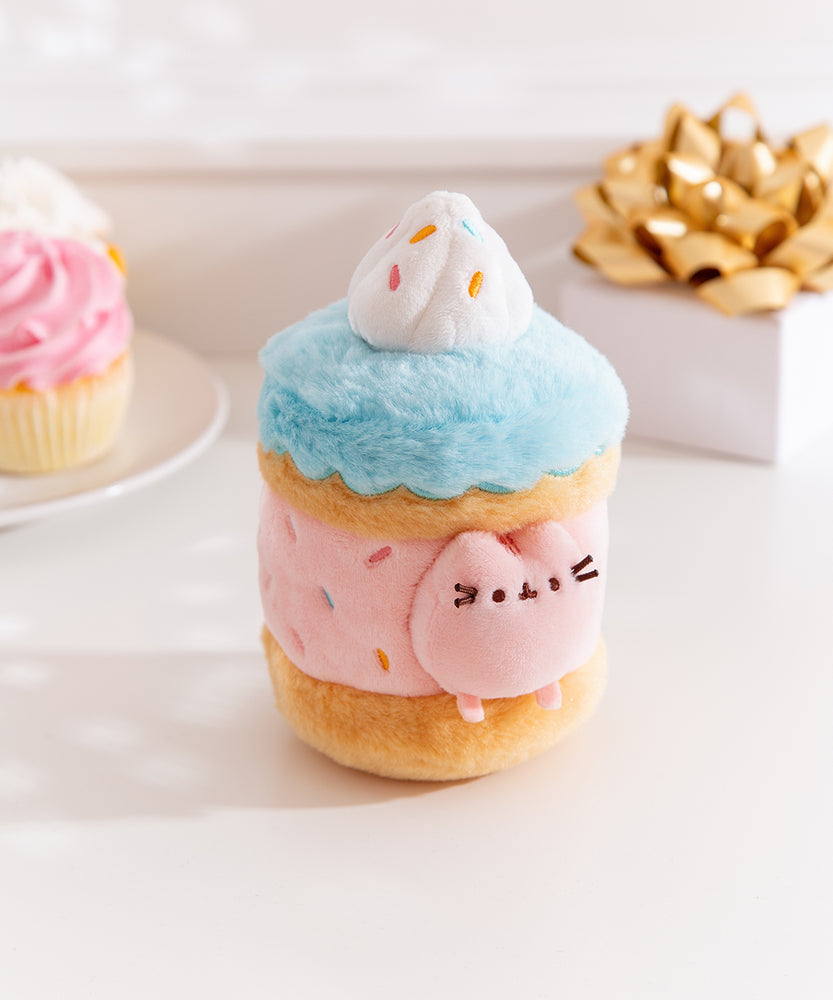 Alternate side quarter view of the Pusheen Sweets Sprinkle Cake Plush Environment. The blue, pink, and brown plush has a removable miniature plush of Pusheen the Cat.  