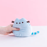 A model’s hand squeezing the Blue Mini Squisheen Plush, demonstrating it’s squishiness.
