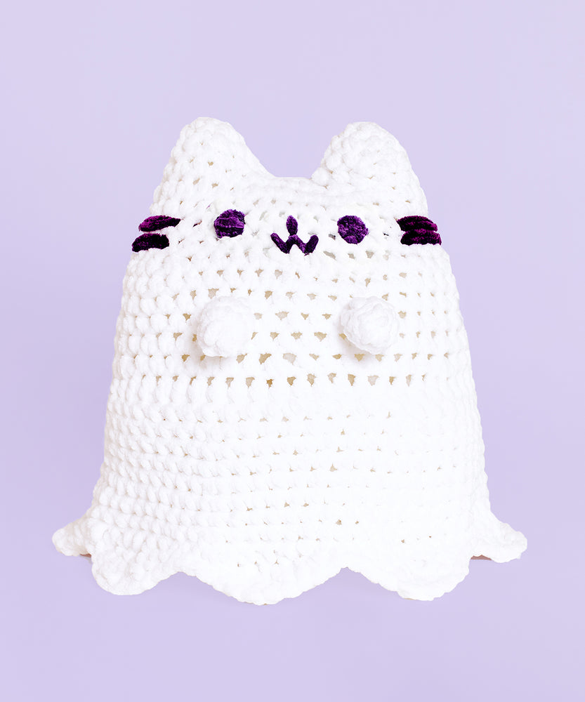A completed Crochet Boosheen plush sitting upright with a lavender background.