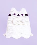 A completed Crochet Boosheen plush sitting upright with a lavender background.