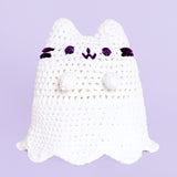 A completed Crochet Boosheen plush sitting upright with a lavender background.