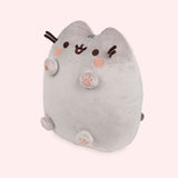 Left quarter view of Pusheen plush. This view shows Pusheen’s four paws extending off her body and to showcase all four bottom of the paws. The plush tail extends slightly off the back of the plush and is peeking out in this angle.