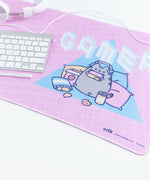 Angled close up of the Gamer Pusheen design on the Gaming Desk Mat. The white headphones, keyboard, and pen are partially visible, sitting on the left hand side of the mat. The Manufacturer details, copyright date and product number are visible on the lower right hand side of the mat.