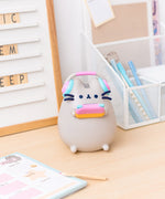 Close-up view of Gaming Lamp. The plastic lamp features Pusheen’s whiskers and paws as well as headphones and a gaming device that extend off the plastic body.  