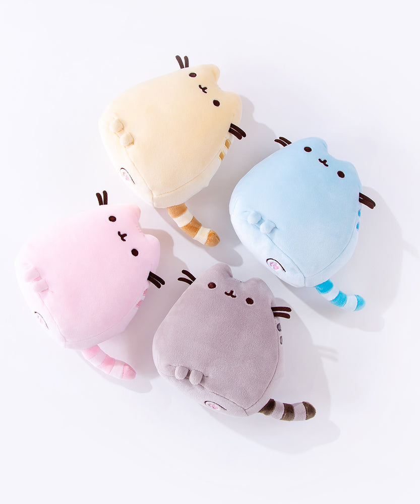 All four Mini Squisheen Plush laying on their backs on top of a white floor, the bottom of the plush partially visible. The flat bottom of the plush features two more feet and with pink paw prints embroidered into the plush.