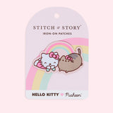 Front view of the Large Patch in it’s backing in front of a light pink background. The backing for the patch is light pink with a pink, yellow and mint rainbow passing behind the patch. The text ‘Stitch & Story Iron-On Patches’ is on the top near the backing’s display hole. At the bottom is a white rectangle with the Hello Kitty x Pusheen collaboration logo. 