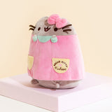 Quarter view of the front of the Pusheen Plush, showing the Hello Kitty x Pusheen collaboration logo on the pocket. The dress goes down to Pusheen's feet, leaving her bottom exposed.