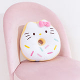 Hello Kitty side of Donut Plush sits on a pink desk chair to demonstrate the scale of the plush. Hello Kitty has brown eyes and whiskers to accompany her classic yellow nose.  