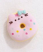 Full front view of Pusheen the Cat side of the reversisble Donut Plush. The strawberry glazed plush toy lays on a light white carpet surface.  