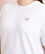 A model wearing a white shirt in a quarter view with the donut patch above the right breast. The patch makes the shirt look like an embroidered tee.