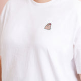 A model wearing a white shirt in a quarter view with the Pusheen patch above the right breast. The patch makes the shirt look like an embroidered tee.