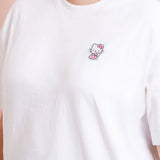 A model wearing a white shirt in a quarter view with the Hello Kitty patch above the right breast. The patch makes the shirt look like an embroidered tee.