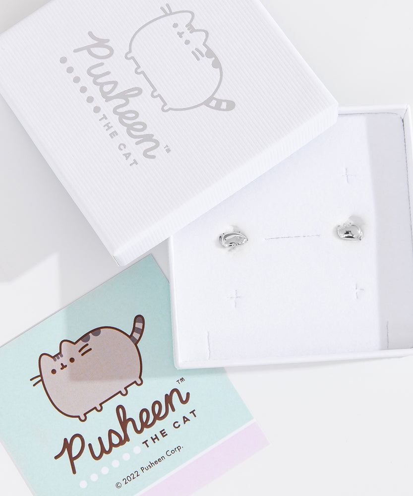 Sterling Silver finish of Pusheen Lazy Stud Earrings in their white packaging box. The earrings are accompanied by the lid of the packaging box and a mint green informational card about the earrings. 