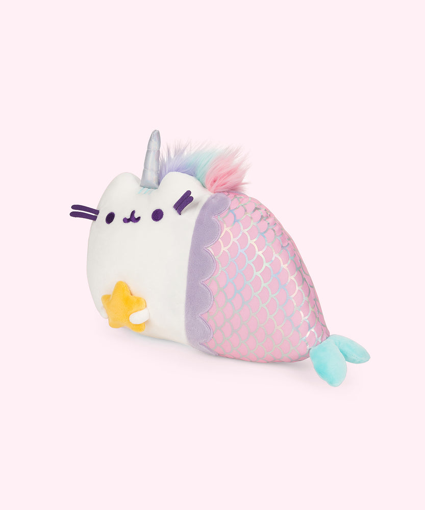 Quarter view of the Magical Lights Mermaid Pusheenicorn Plush facing the left in a light pink space. 
