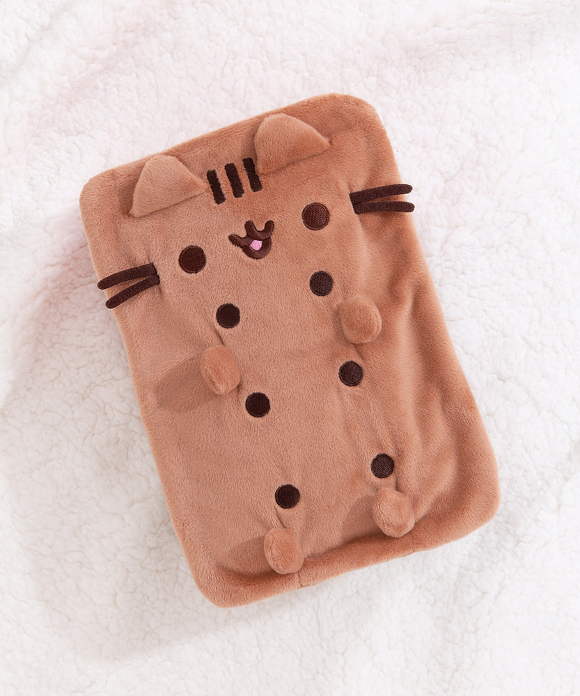 Top view of the squisheen plush shows off Pusheen’s brown face and four paws. Pusheen plush lies on a white surface.  