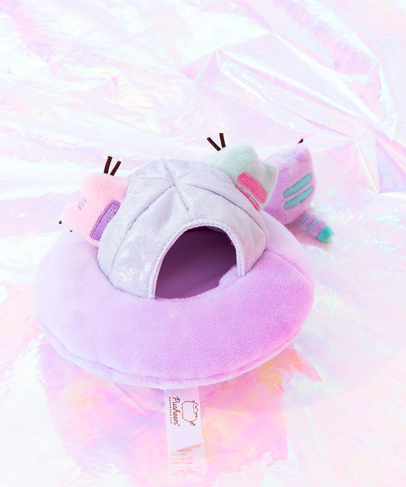 Back overhead view of the Mini Lilac Pusheen takes the first steps onto the holographic ground while the Mint and Pink Pusheen look on from the safety of their plush ship. The Mini Pastel plush all have two back stripes, along with a striped tail. At the back of the UFO there is a information tag attached to the bottom of the plush.