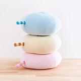 Quarter back view of the three Round Squisheen Plush stacked on top of one another, sitting on top a wooden floor in front of a white background. All plush have a striped tail in the middle of their butts which point straight out and line up perfectly with one another.