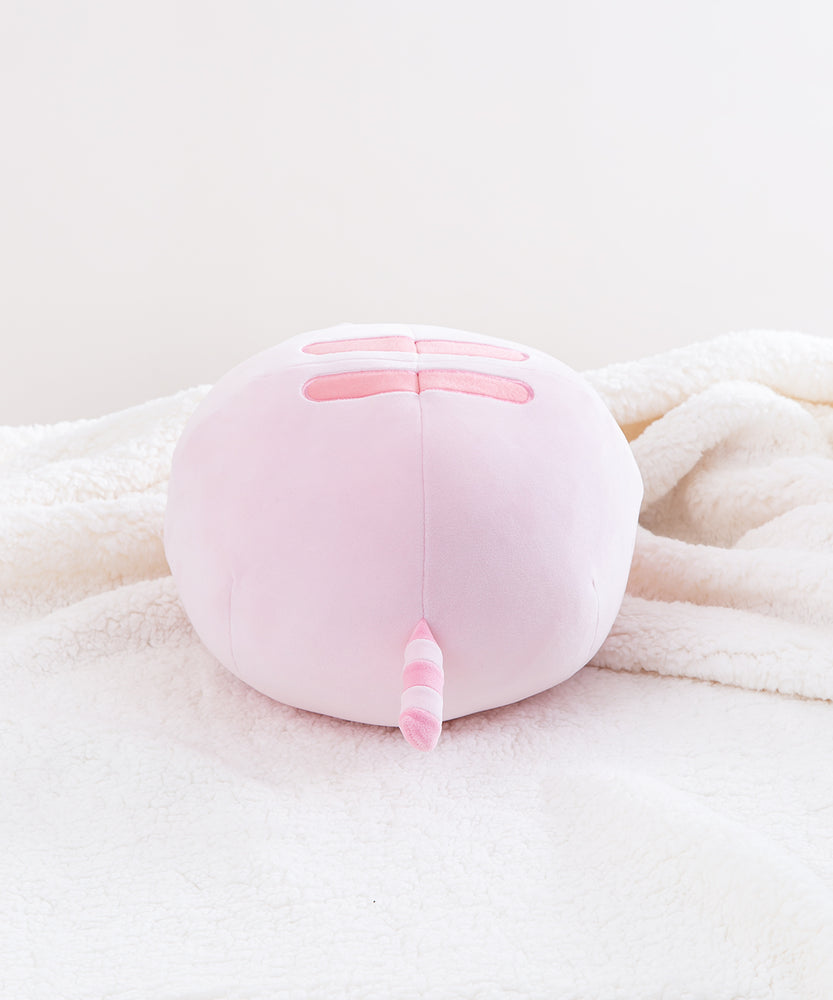 Back view of the Pink Round Squisheen sitting on top a fluffy white blanket. All the stripes on Pink Pusheen are a dark pink.