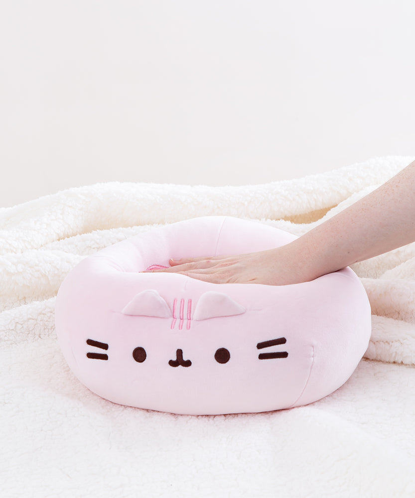 A model’s hand pressing down on the Pink Round Squisheen, demonstrating the plush’s squishiness. 