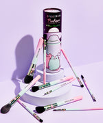 Pastel Pusheen 10-Piece Makeup Brush Set fanned out on white pedestals. All makeup brushes and storage tube sit in front of a purple background. Brush set includes powder brushes, eyeshadow brushes, and eyeliner brushes.