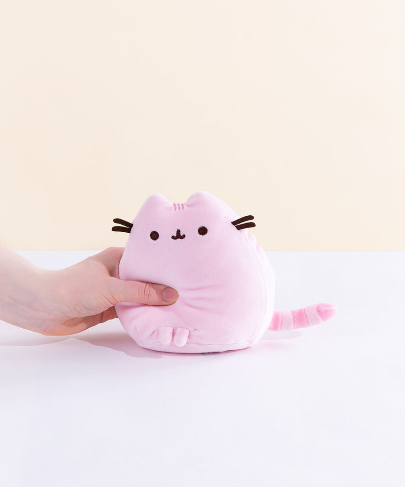 A model’s hand squeezing the Pink Mini Squisheen Plush, demonstrating it’s squishiness