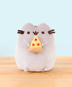 Pusheen sitting upright, mouth open, her two top nub paws holding a plush pepperoni pizza slice, and her bottom nub feet rest at the bottom.