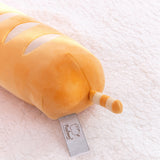 Back view of the baguette bread squisheen. The elongated plush has light cream wavy stripes on the top of the plush. At the back bottom of the plush is a light brown and cream striped tail. 