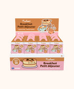 Pusheen Breakfast Surprise Plush cardboard display case holding the surprise boxes. The individual surprise boxes are pink with pancake, latte, and orange juice Pusheens. The box display is brown and pink, featuring an illustration of Pancake Pusheen.