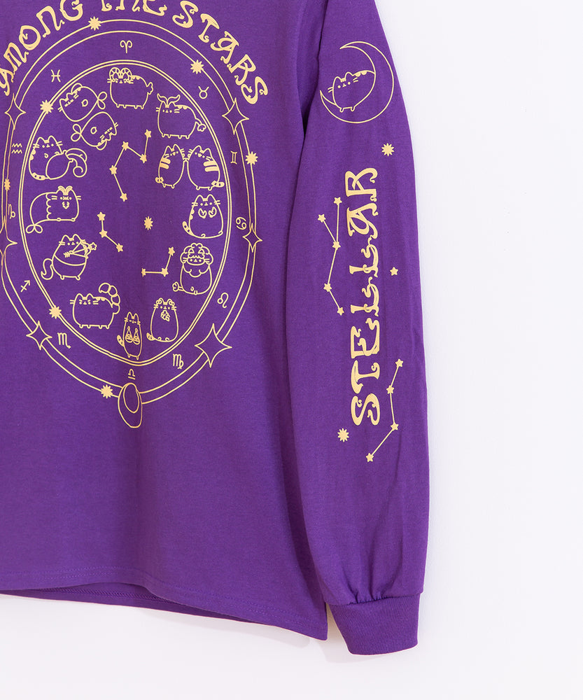 Close-up view of left sleeve of the Pusheen long-sleeve tee. The gold printed graphic features Pusheen lounging on a crescent moon and the phrase “Stellar” surrounded by stars and star constellations. 