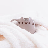 The Pusheen Character Mug tucked cozily among the folds of a fluffy white blanket.