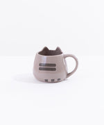 The back of the Pusheen Character Mug in front of a white background. On the back of the mug there are two dark grey back stripes printed in the middle of the mug’s back. At the bottom there is a trio of small dark grey squares, creating the illusion of Pusheen’s tail pointing to the right. The rim of the mug at the back is smooth and round.