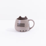 The back of the Pusheen Character Mug in front of a white background. On the back of the mug there are two dark grey back stripes printed in the middle of the mug’s back. At the bottom there is a trio of small dark grey squares, creating the illusion of Pusheen’s tail pointing to the right. The rim of the mug at the back is smooth and round.