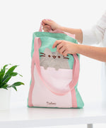A model holds the Pusheen Deluxe Tote Bag open to show the scale and size of the bag.  