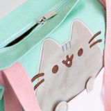 Close-up view of the zipper-closure and Pusheen applique. The tote bag closes shut. The applique of Pusheen is grey velour.  
