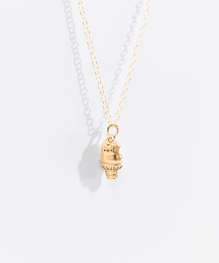 A close-up view of the side of the Pusheen Dipped Cone Necklace in Gold Vermeil. Pusheen the Cat’s classic face and whiskers have been included in the dipped ice cream cone charm. 