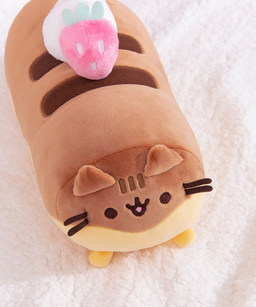 Top view of the plush shows off the éclair toppings: a pink strawberry and a dollop of whipped cream sitting atop Pusheen's brown back stripes.