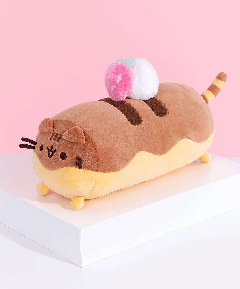 Left quarter view of dessert inspired plush. This view shows Pusheen’s long cylinder body and two-toned color details. The top of the plush is light brown to imitate chocolate drizzle.