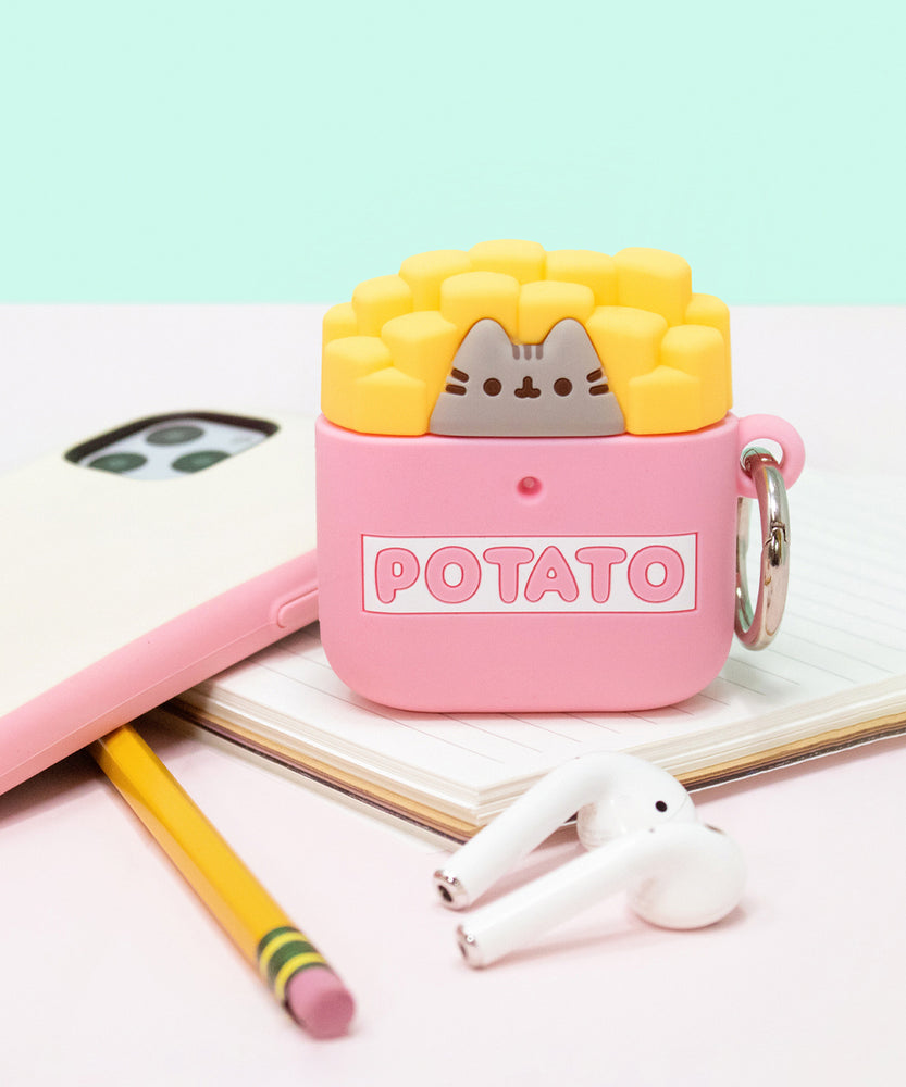Front view of the Pusheen French Fries Airpods Case placed on a notebook surrounded by an iPhone, pencil, Apple Airpods. 