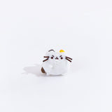 Full view of the mini annoyed white cat plush from the collectors set. The cat is all white, save for a brown embroidered dot on it’s left side, an embroidered dark brown line over its left ear and an embroidered yellow dot over their right ear. The plush has angry eye brows embroidered above their eyes, and their right paw is lifted up towards their mouth.