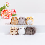 Six mini cat plushes lined up in two rows of three in front of a white background with a pink peony laying on the left. The top row features a brown winking cat with white paws and snout, Pusheen, and a worried looking yellow cat with a white belly. The bottom row features a Siamese cat, a white cat with brown and orange spots, looking annoyed and covering their nose, and a happy looking skunk.