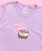 A close-up view of the tee’s screen print graphic. Ice Cream Cake Pusheen is a short cylinder shape with white and brown striped details with light brown balls atop the white top. The ice cream cake features Pusheens’ face printed on the front, her striped tail sticking out from the back, her paws at the bottom of the cake. The word ‘Chill’ is printed in white in a light pink heart with a white outline. The pink heart accompanies the ice cream cake in the center of the tee shirt. 