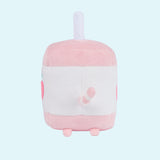 On a light blue background, the Juice Box Sips Plush shows off its white straw detail, plush pink feet, and white and pink striped tail that extends slightly off the body of the plush. 