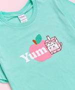 A close-up view of the tee's screen print graphic. Pusheen is shown as a Juice Box with an apple accompanying the character.  