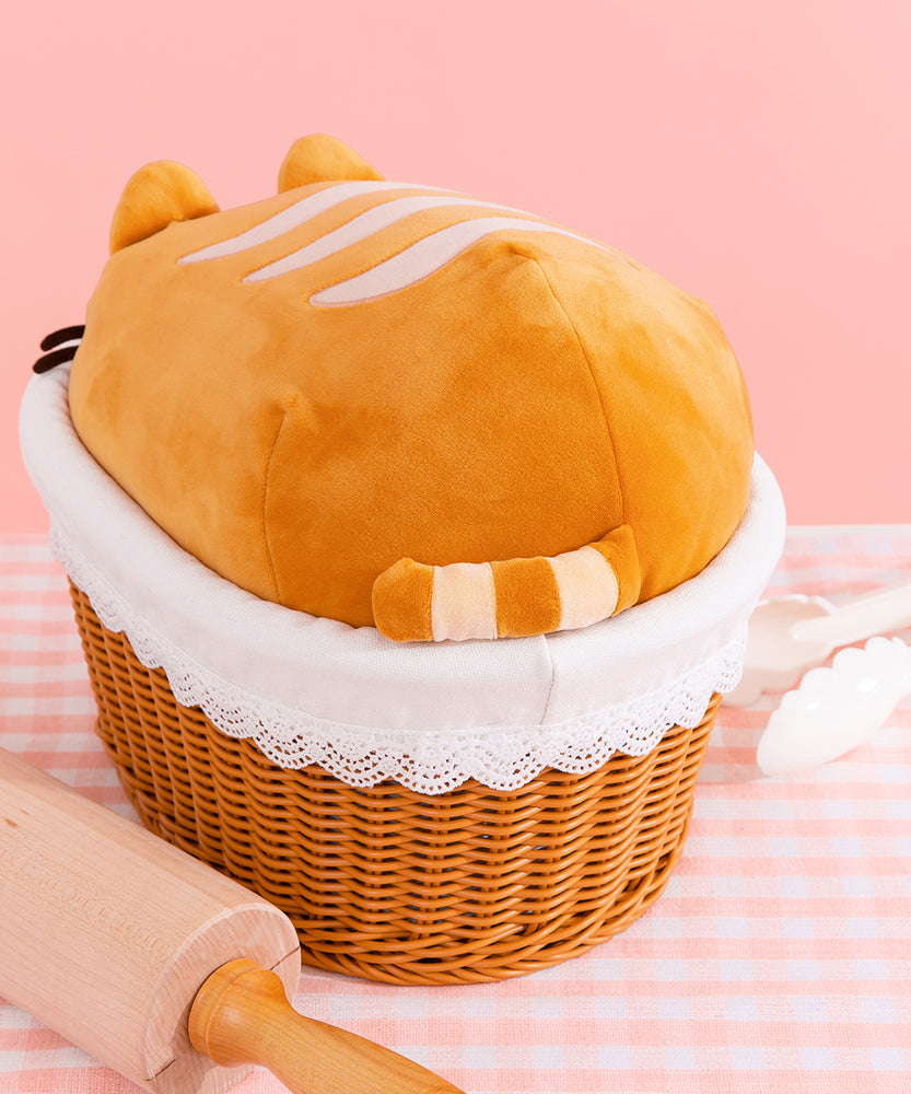 Back view of the loaf plush. The back end of the squisheen sits slightly out of the breadbasket to show off the plush tail attached to the back. 